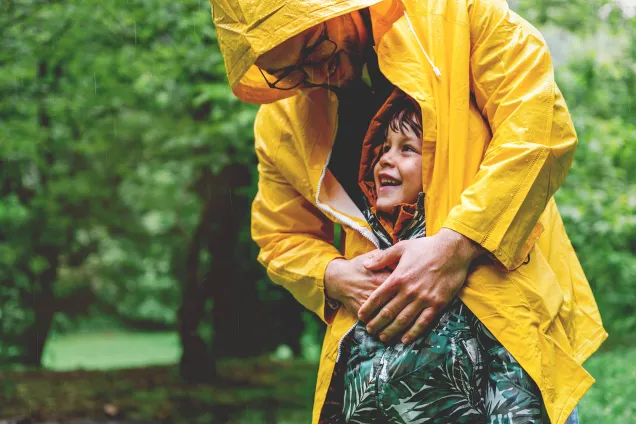 dad shelters child from rain with his coat 